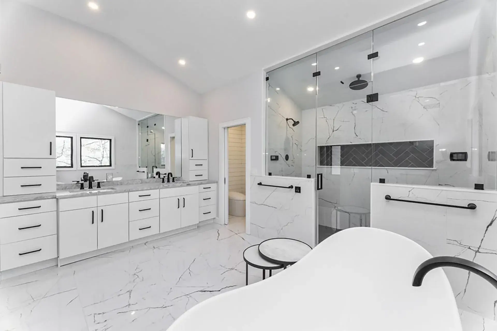 Marble bathroom with a long double vanity, freestanding tub and glass shower