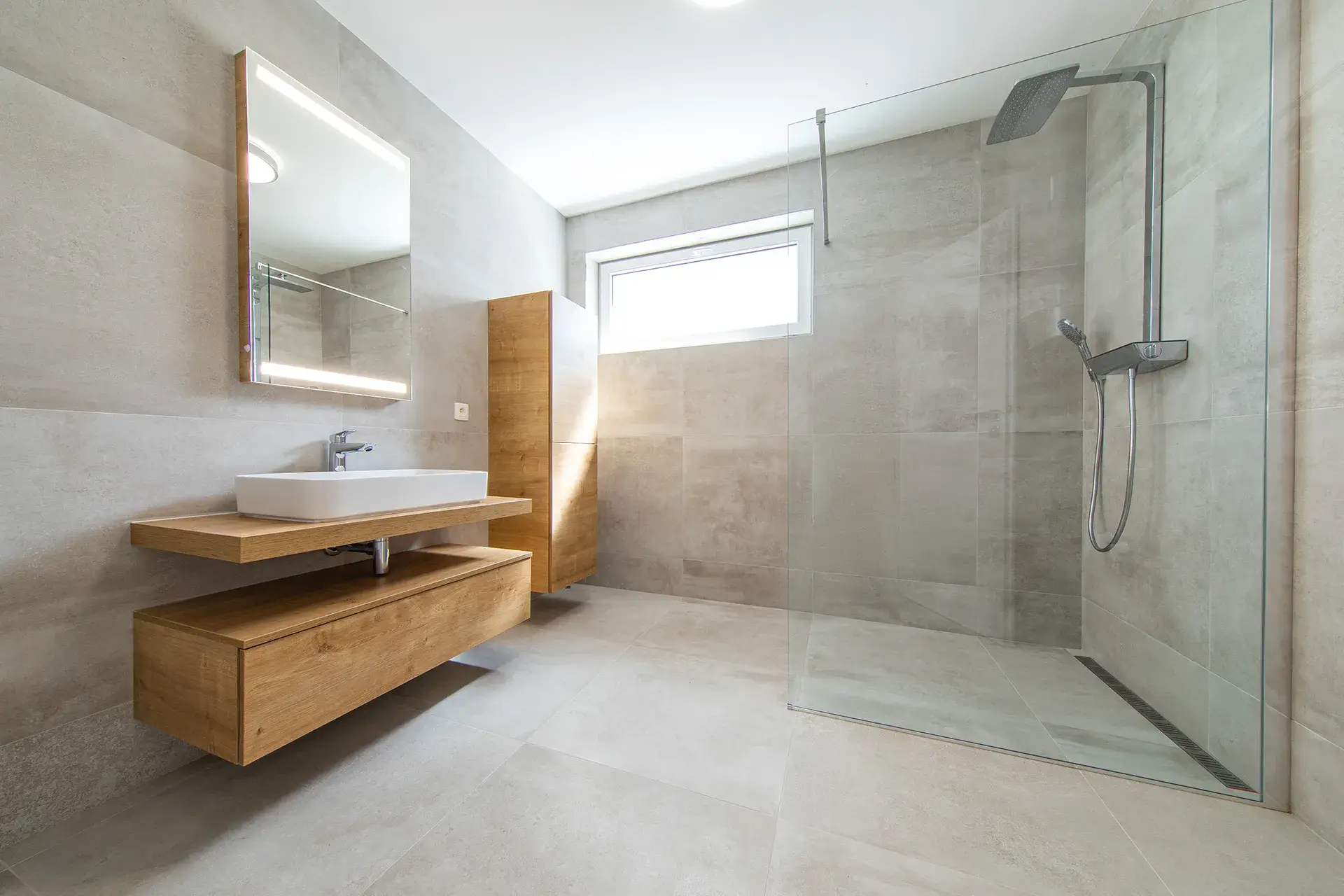 Bathroom with a wood floating vanity, vessel sink and a glass walk in shower