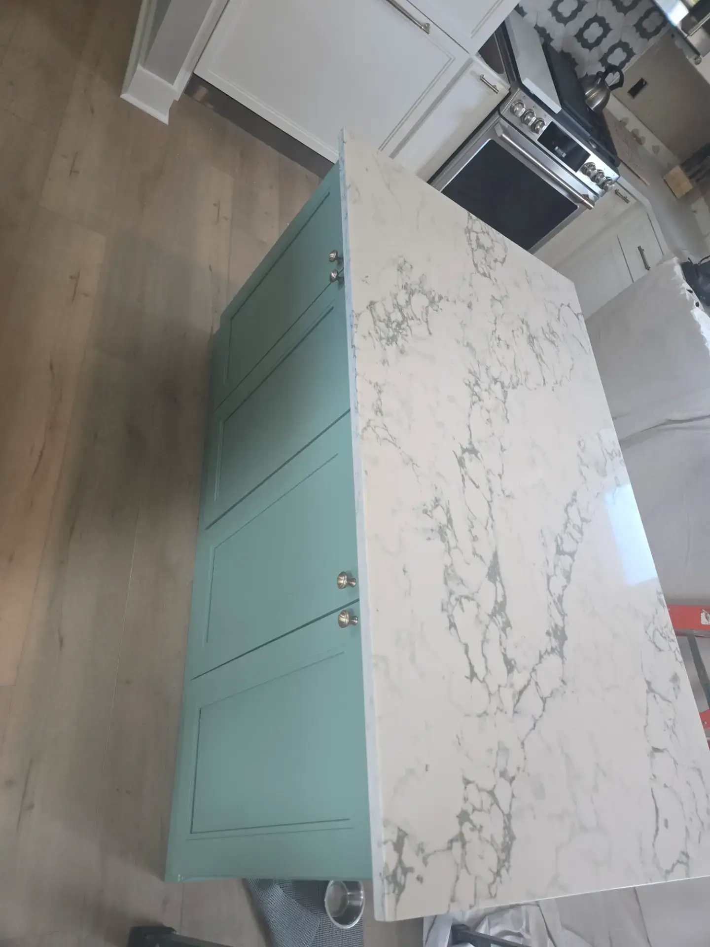 Veined stone countertop edge above a teal cabinet front
