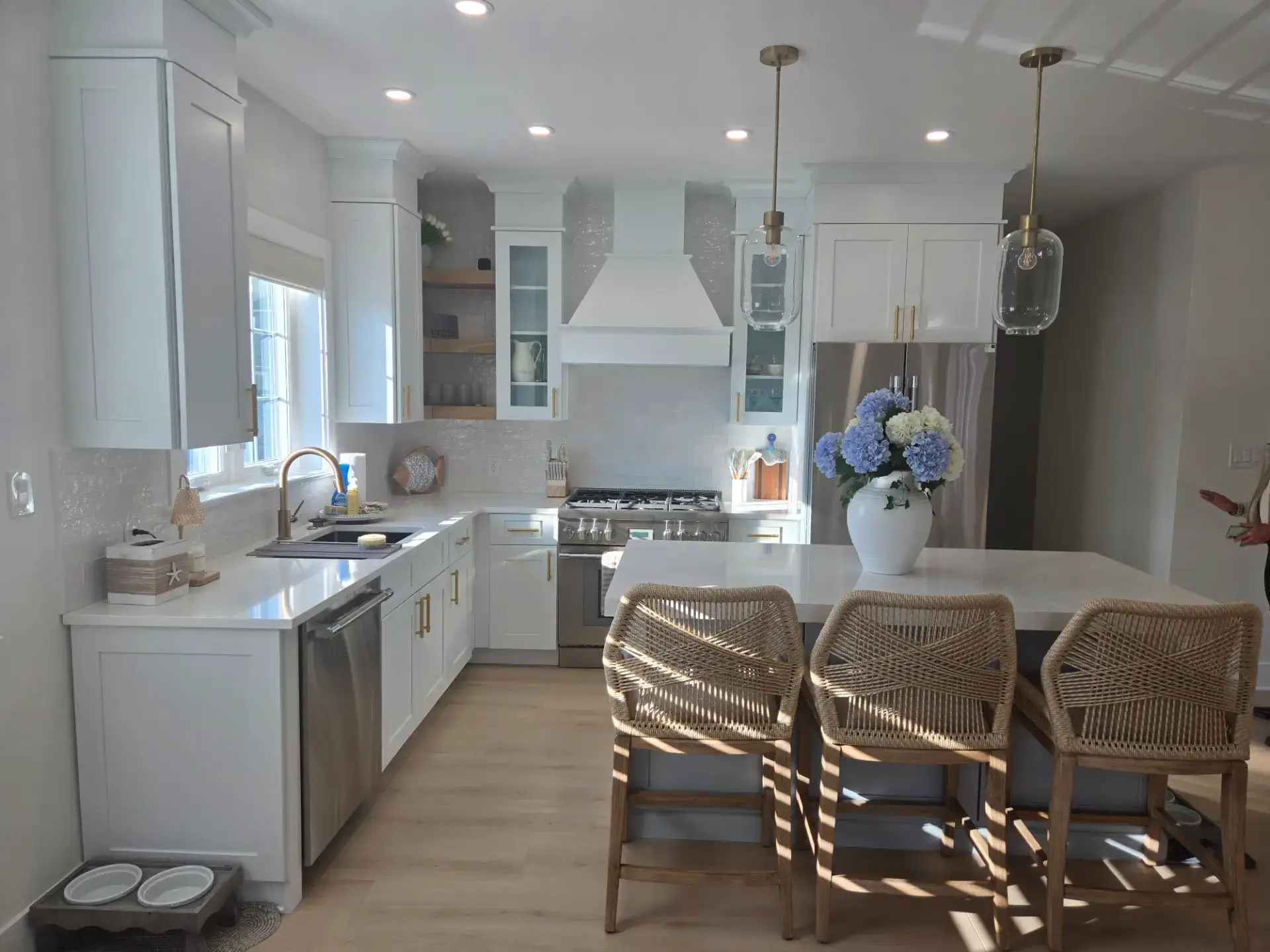 White kitchen with a custom range hood and a marble topped island