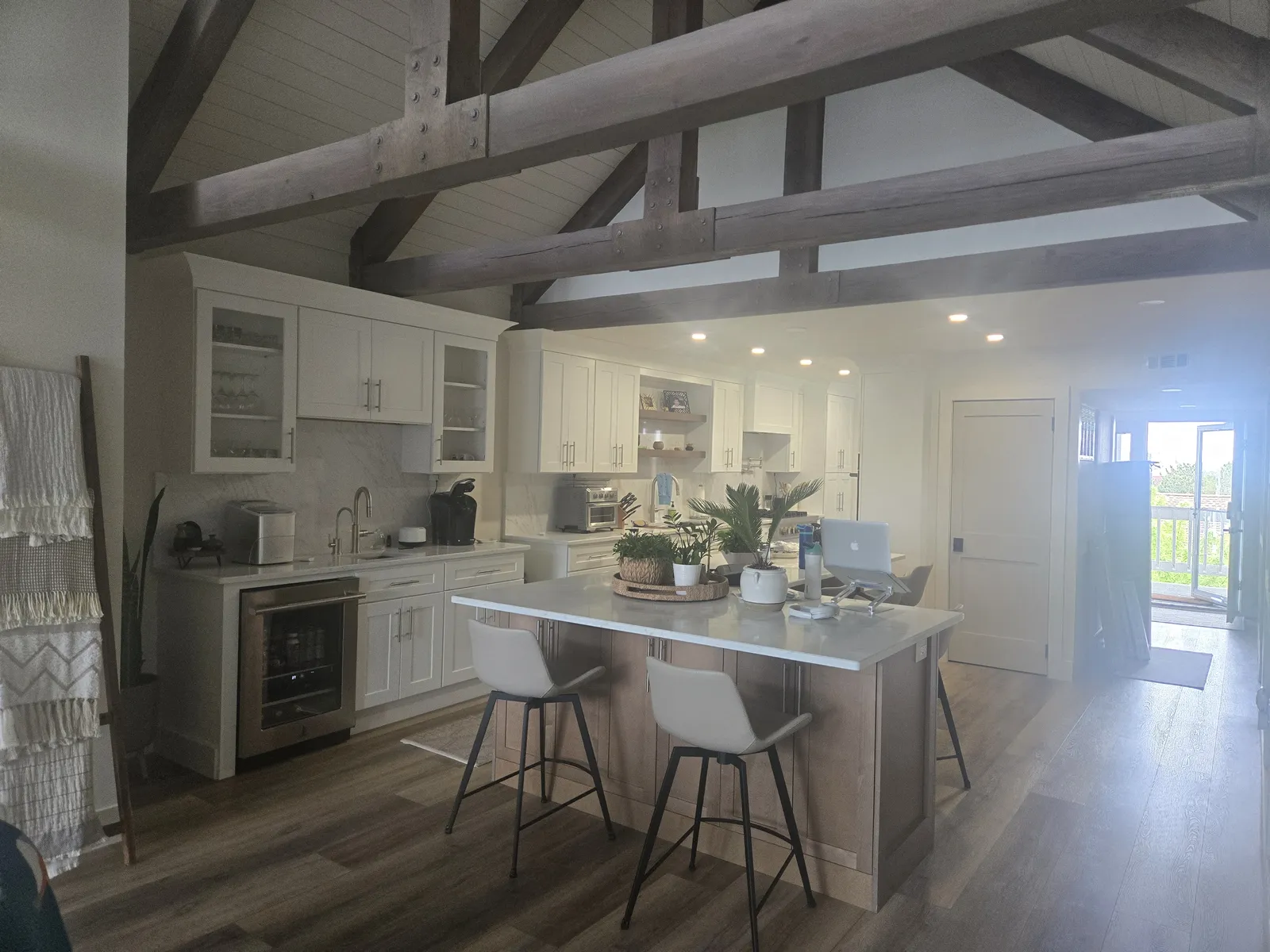 Kitchen with white cabinetry under exposed wood beams